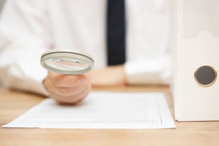 someone holds a magnifying glass up to a legal document