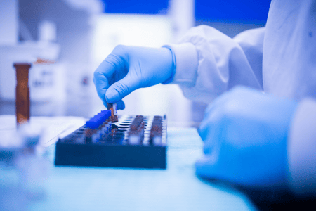 test tubes and hand with blue gloves