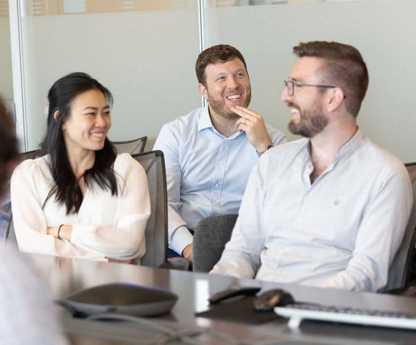 Three people smiling while sitting in an office