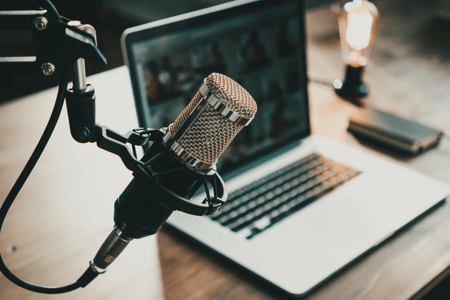 a microphone is featured above a laptop insinuating a recording session